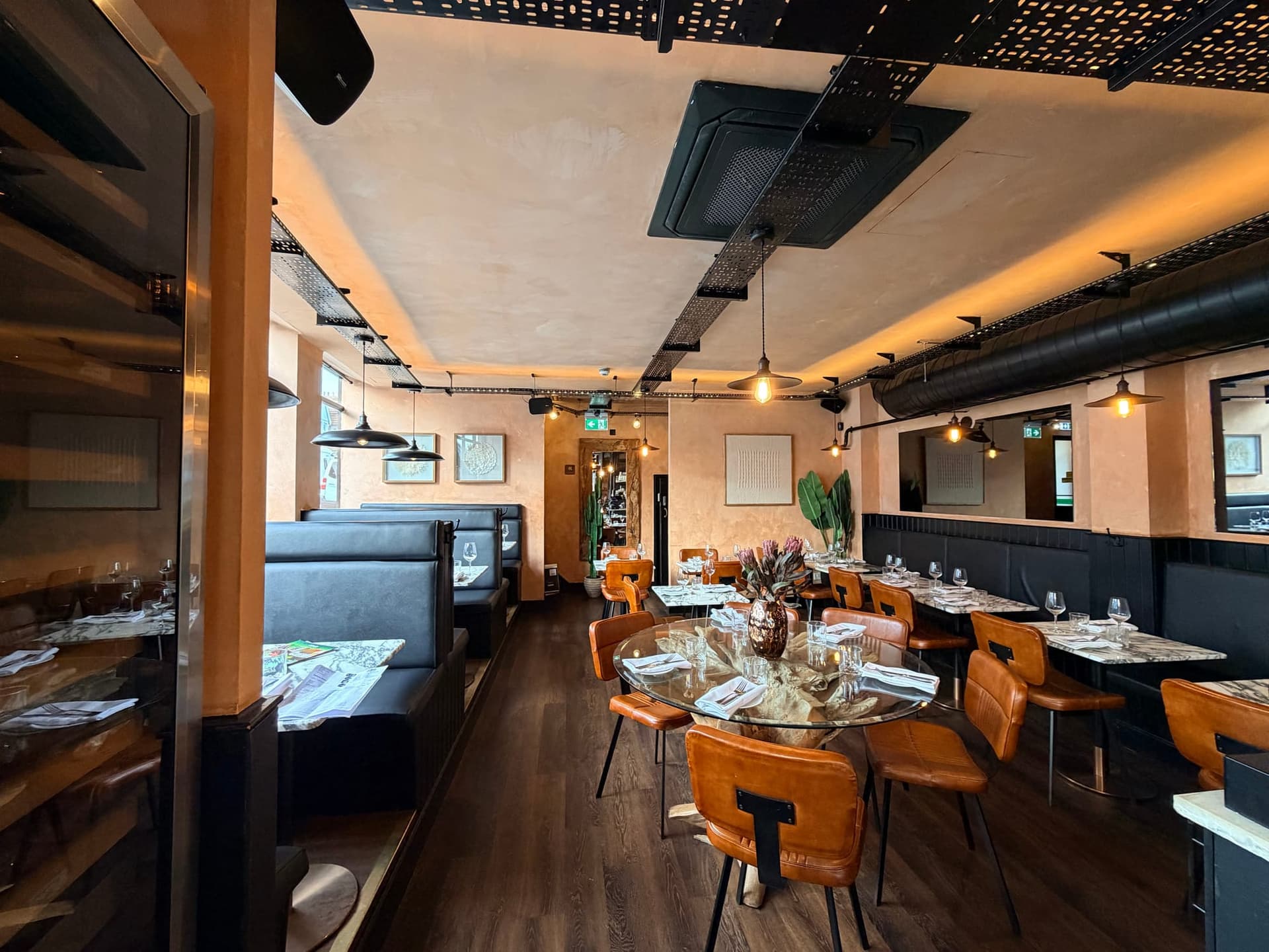 The NORA dining room with terracotta walls, leather chairs and filament lamps