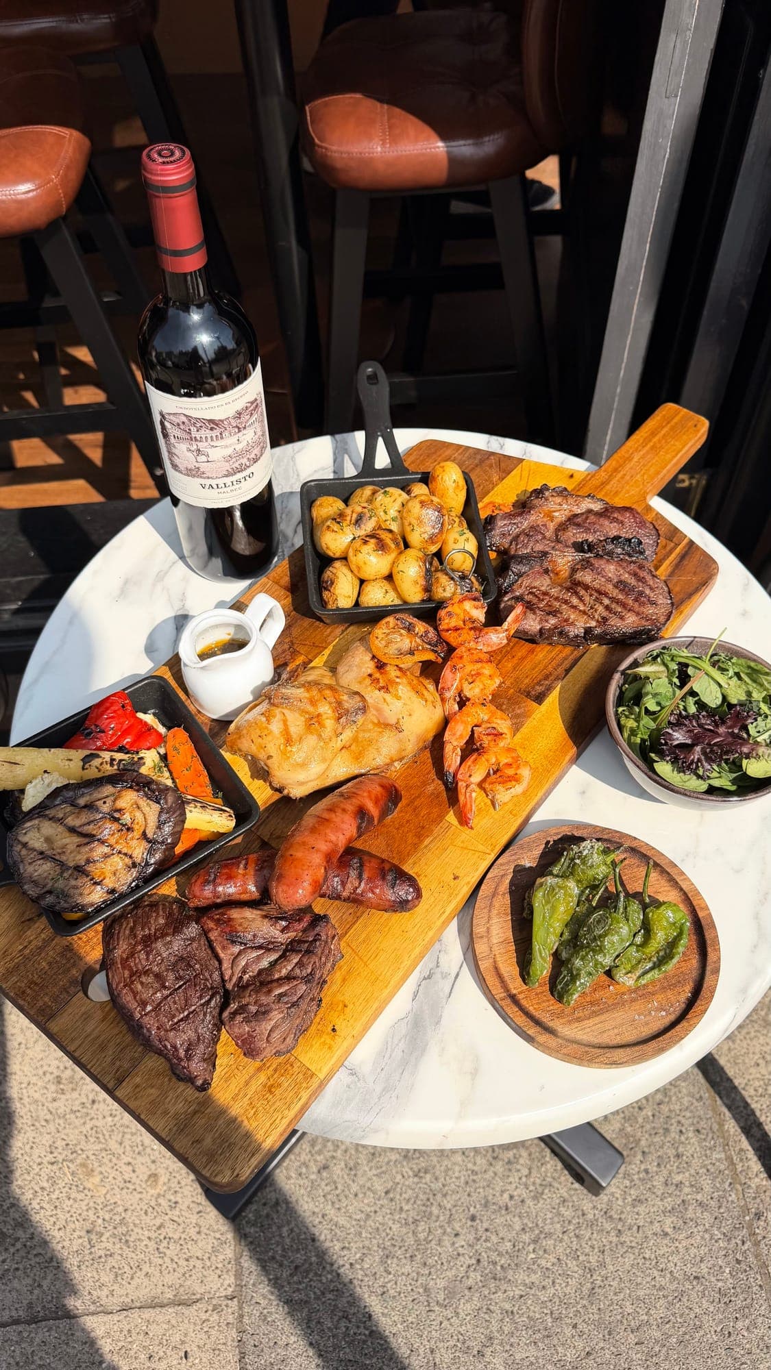 Half a roast chicken, prawn skewers, chorizo and charred steaks on a wooden Sunday mixed grill board